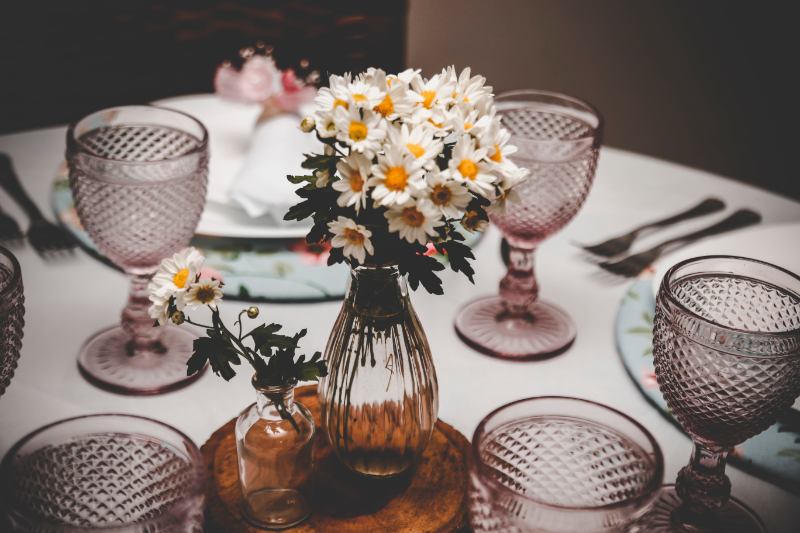 Table setting with two vases of daisies as centerpieces